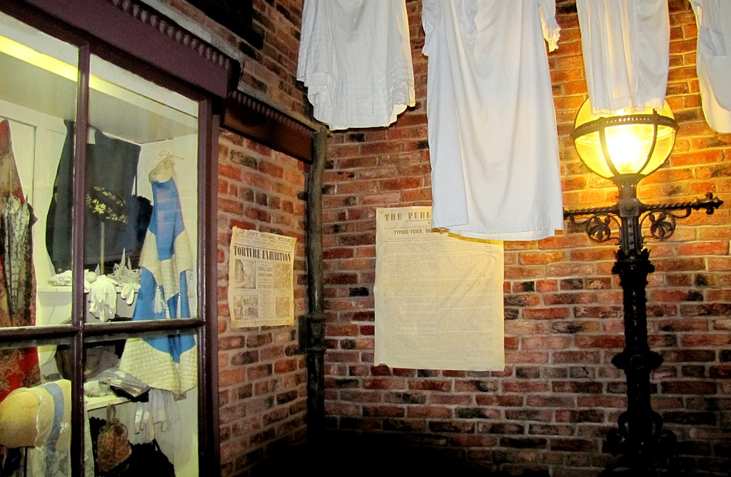 A little dead end alley, with washing hanging from the higher floors. The two posted papers are a notice about how to avoid disease from city water, and an advertisement for an exhibition of torture implements and accounts.